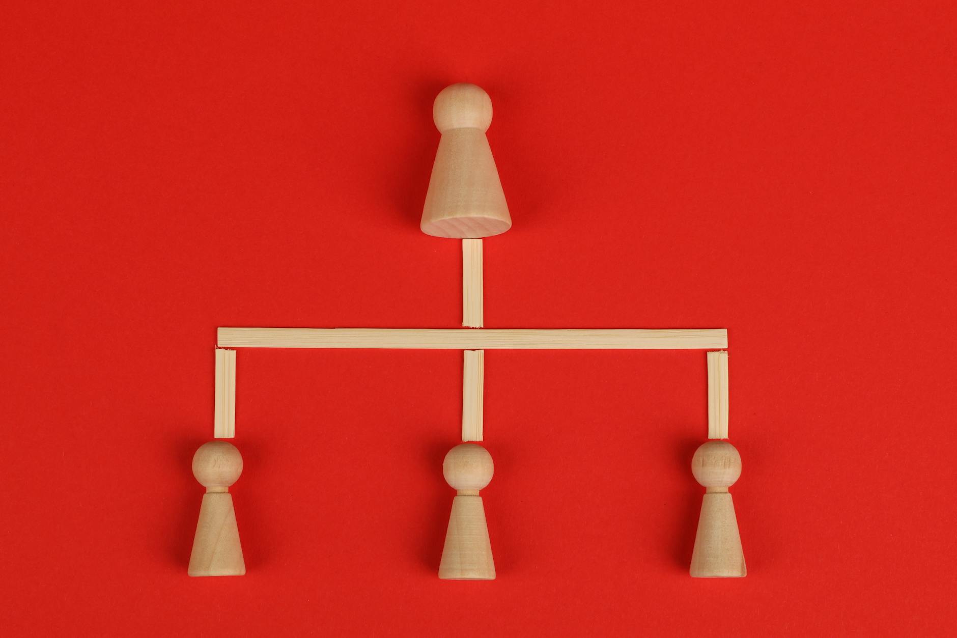 Drewniane pionki ustawione hierarchicznie na intensywnie czerwonym tle