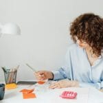 Kobieta w biurze liczy odsetki z lokaty na kalkulatorze