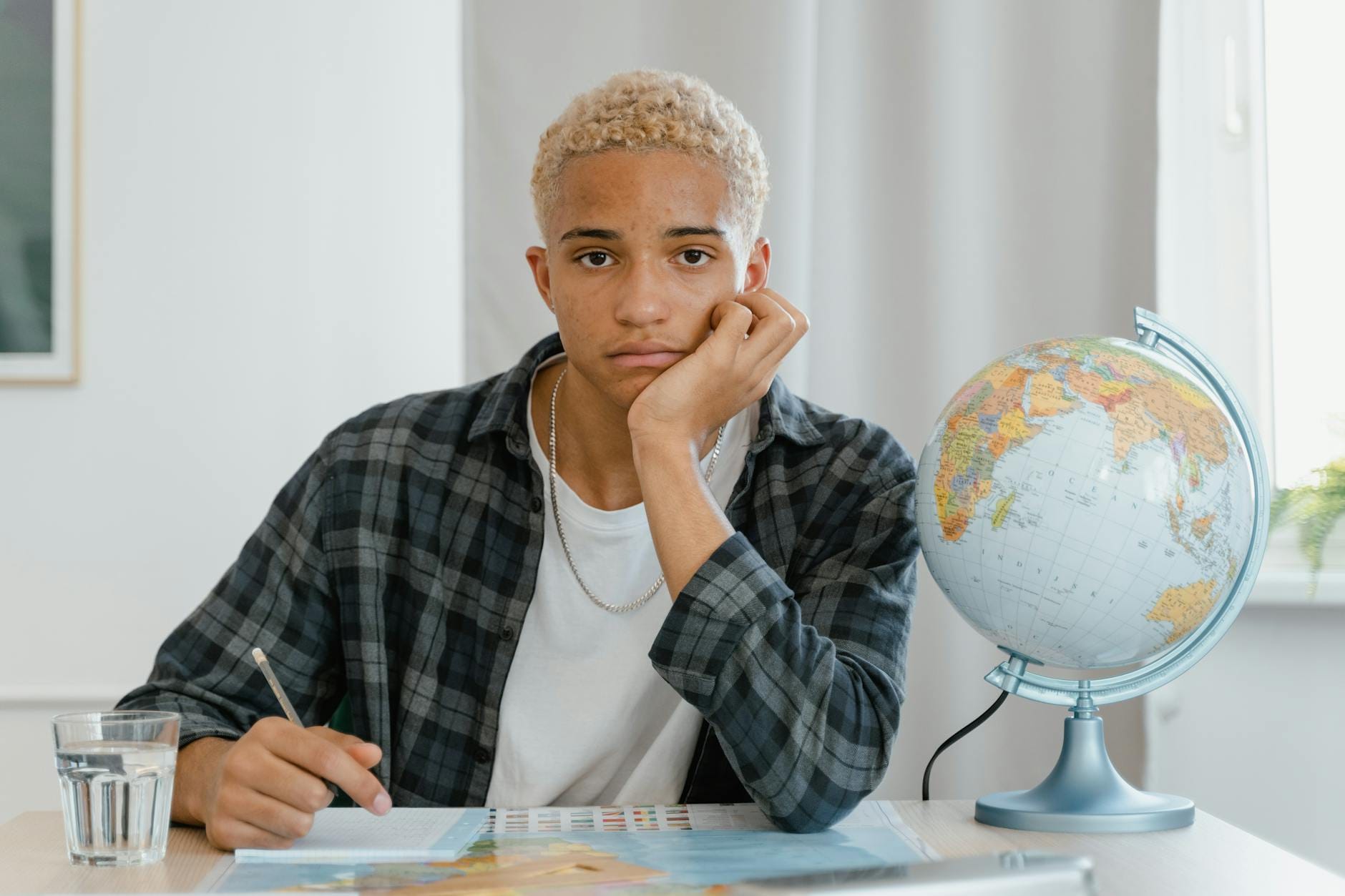 Młody dorosły przy biurku uczy się geografii z globusem