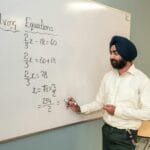 Nauczyciel na tle tablicy wyjaśnia ułamki dziesiętne i zwykłe