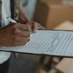 Osoba wypełniająca formularz na podkładce z klipsem