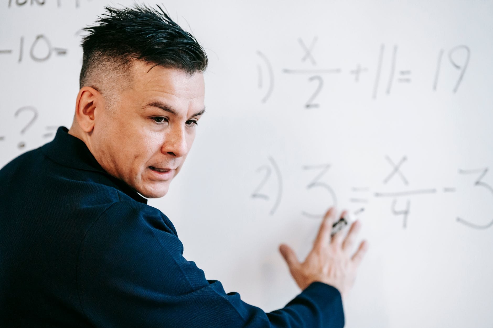 Nauczyciel matematyki tłumaczy równania algebraiczne na białej tablicy