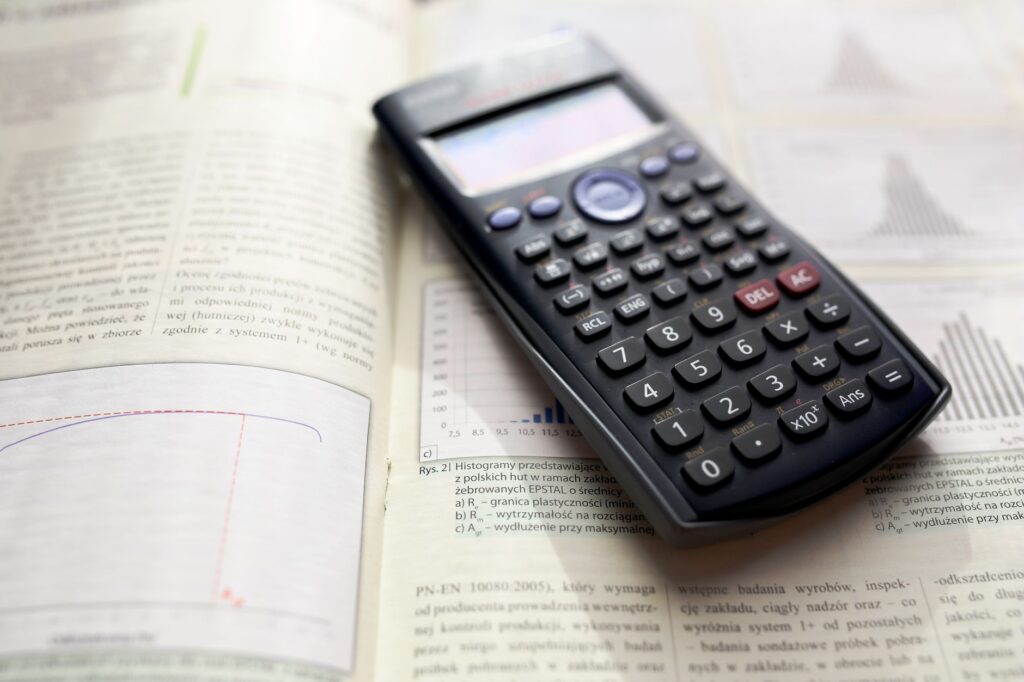 Kalkulator graficzny na otwartym podręczniku matematyki z wykresami i równaniami